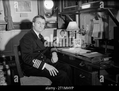 Kapitän (d) ein K Scott - Moncrief, Rn, an seinem Schreibtisch in seiner Kabine an Bord der HMS Faulknor. 10. Februar 1943, in Scapa Flow. Stockfoto