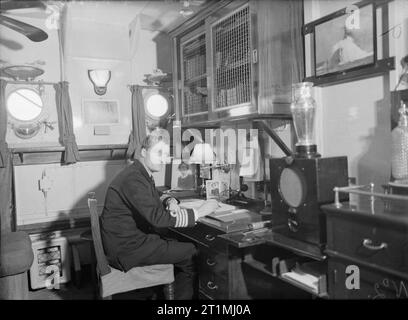 Kapitän (d) ein K Scott - Moncrief, Rn, an seinem Schreibtisch in seiner Kabine an Bord der HMS Faulknor. 10. Februar 1943, in Scapa Flow. Stockfoto