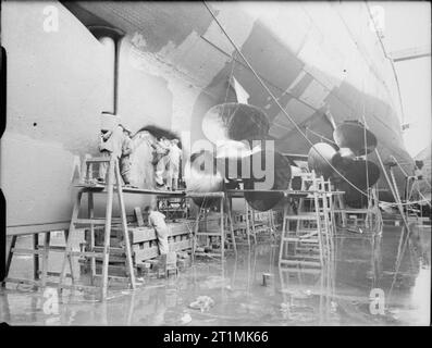 Die Royal Navy während des Zweiten Weltkriegs Handwerker bei der Arbeit auf das Seitenruder und die Propeller von HMS REPULSE während Ihrer einbauen im Trockendock. Beachten Sie, Ihre Größe zu den Männern in der Nähe verglichen. Stockfoto