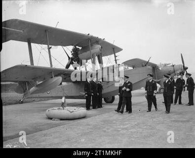 Die Royal Navy während des Zweiten Weltkriegs HM König George VI, in der Uniform eines Admiral der Flotte, die Inspektion Inspektion eines Supermarine Walrus amphibischen Flugzeug und seine Crew bei der Royal Naval Air Station Hatston während seiner viertägigen Besuch der Home Fleet in Scapa Flow. Eine Fairey Albacore kann im Hintergrund gesehen werden. Stockfoto