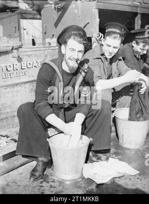 Das tägliche Leben an Bord der HMS Eitelkeit, Oktober 1940 ein führender Seaman, mit Bart und das Rauchen einer Pfeife, ist einer von drei Matrosen ihre Kleider waschen. Sie sitzen auf dem Deck der HMS Eitelkeit, Motorboot Storage Area ihre Kleider waschen in Metall Eimer. Stockfoto