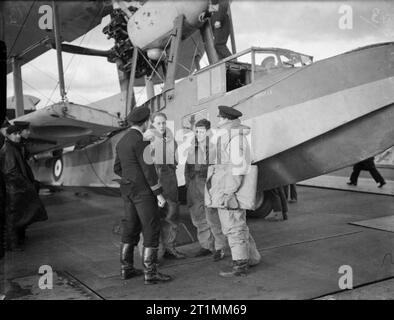 Die Royal Navy während des Zweiten Weltkrieges die Besatzung; Pilot, Beobachter, und air Gunner, Bericht an den kommandierenden Offizier auf dem Erhalten von ihren Supermarine Walrus Flugzeuge an Bord der Flugzeugträger HMS ARGUS. Hinweis Die Mitglied der Schiffsbesatzung im Cockpit. Stockfoto