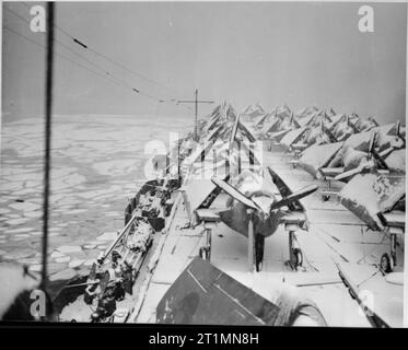 Die Royal Navy während des Zweiten Weltkriegs auf der Suche nach Insel der Flugzeugträger auf dem Schnee bedeckt und die überfüllten Deck von HMS KAISER, als sie ihren Weg durch das eisige Wasser vor Neufundland mit ihrer Fracht von Grumman Hellcat Kämpfer für die Fleet Air Arm gemacht. Pack-Eis können im Meer gesehen werden. Stockfoto