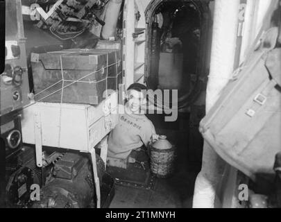 Die Royal Navy während des Zweiten Weltkriegs "Spirituosen", lächelnd G R Gill aus Durham, die Rum jar aus der Luke von HMSM SERAPH, während das U-Boot in Holyhead Hafen war. Das Wort Geordie über seine Jumper geschrieben wird. Stockfoto