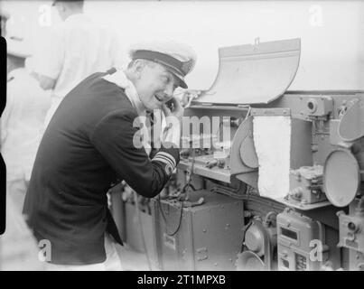 Die Royal Navy während des Zweiten Weltkriegs den Torpedo Officer und Principal Control Officer, findet Zeit für eine Rasur mit einem elektrischen Rasierer, bei seiner Aktion Station während einer Ruhepause an Bord der HMS Sheffield, während das Schiff ist ein Malta eskortieren Konvois im Mittelmeer (HELLEBARDE). Stockfoto