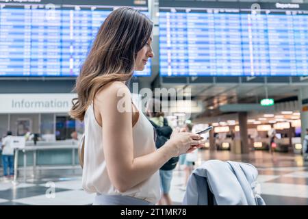 Frau, die Informationen über Abflüge am Flughafen sucht Stockfoto