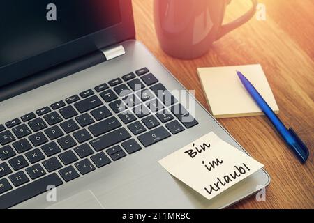 14. Oktober 2023: Schreibtisch mit Tasse und Laptop mit Hinweis: Am auf Urlaub FOTOMONTAGE *** Schreibtisch mit Tasse und Laptop Computer mit Notiz: Bin im Urlaub FOTOMONTAGE Credit: Imago/Alamy Live News Stockfoto