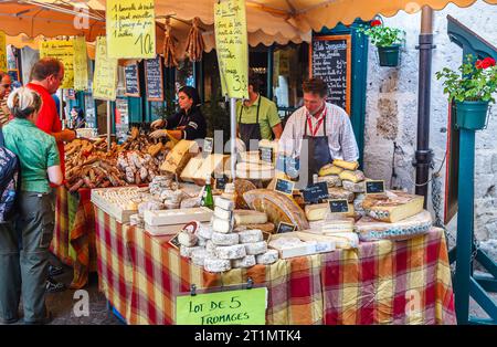 Käse- und Fleischstände und Ausstellungen lokaler Produkte auf einem Außenmarkt in Annecy, Frankreich, mit einer großen Auswahl an Hart- und Weichkäsesorten Stockfoto