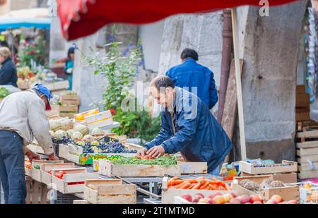 Ein lokaler französischer Stallhalter arrangiert seinen Verkaufsstand für frisches Obst, Gemüse und Obst auf dem Lebensmittelmarkt in der Altstadt von Annecy, Frankreich Stockfoto