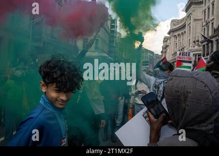 London, Großbritannien. 14. Oktober 2023: Ein kleiner Junge wendet sich von Rauchfackeln ab, die von pro-palästinensischen Demonstranten im Zentrum von London, Großbritannien, bei einer Demonstration gegen israelische Angriffe auf Gaza gehalten werden. Stockfoto