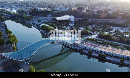 Fantastischer Blick auf die Stadt Tiflis mit dem Fluss Kura, der Brücke des Friedens, dem Rike Park und dem Präsidentengebäude bei Sonnenaufgang Stockfoto