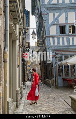 Dinan, Frankreich – Juni 2008: Dame im roten Schaufenster Shopping Place des Merciers Stadtzentrum mit Kopfsteinpflasterstraßen, gesäumt von mittelalterlichen Holzhäusern Stockfoto