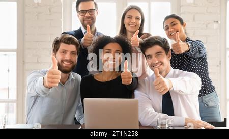 Fröhliche junge multiethnische Kollegen posieren für Porträt am Arbeitsplatz Stockfoto