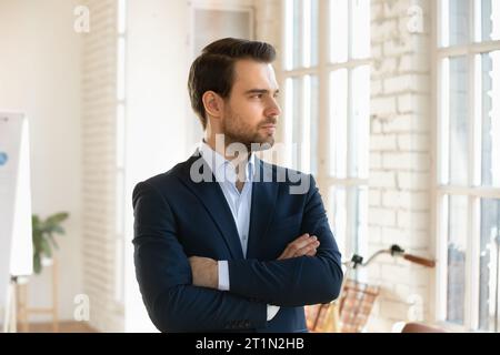 Ernsthaft gutaussehender Geschäftsführer posiert mit gefalteten Händen Stockfoto