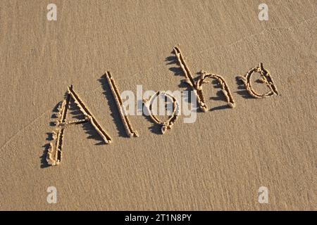 Aloha schrieb in den Sand am Strand. Aloha ist ein berühmter hawaiianischer Gruß. Stockfoto