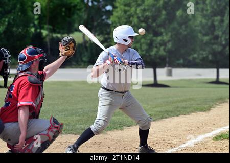 Spring Grove, Illinois, USA. Ein Batter, der einen hohen Spielraum für einen Ball aus der Schlagzone herausnimmt. Stockfoto