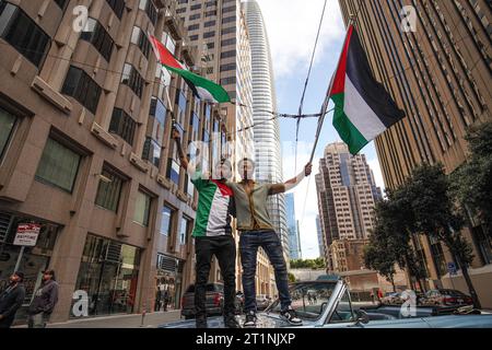 San Francisco, Usa. Oktober 2023. Zwei Männer stehen auf einem Auto und schwenken während des marsches die Flaggen Palästinas. Die Anhänger Palästinas schließen sich zu einer Kundgebung zusammen und marschieren auf den Straßen von San Francisco, um ihre Solidarität mit der Bevölkerung in Gaza und anderen vom Konflikt mit Israel betroffenen Gebieten zum Ausdruck zu bringen. Die Teilnehmer erheben ihre Stimme und singen Slogans wie "freies Palästina" und "das ist kein Krieg. Das ist Völkermord, als sie auf den Straßen marschieren. Die Organisatoren behaupten, dass sich etwa zehntausende Menschen dem marsch anschließen. Quelle: SOPA Images Limited/Alamy Live News Stockfoto