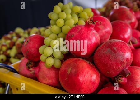 Frische grüne Trauben und Granatäpfel in Kisten, die auf einem Bauernmarkt in San Francisco, Kalifornien, in loser Schüttung verkauft werden Stockfoto