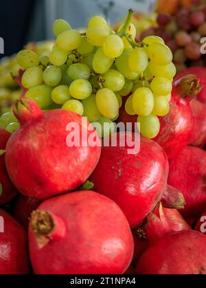 Frische Trauben und Granatäpfel in Kisten, die auf einem Bauernmarkt in San Francisco, Kalifornien, in loser Schüttung verkauft werden Stockfoto