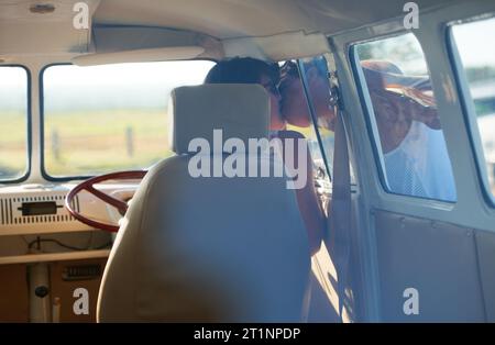 Caravan, Transport und Paare küssen auf Roadtrip, Reisen und Urlaub mit Menschen in Beziehung und Engagement. Liebe, Intimität und Freiheit auf Stockfoto