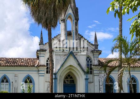 Vorderansicht einer historischen Kirche mit Palmen und blauem Himmel mit Wolken, Serro, Minas Gerais, Brasilien Stockfoto