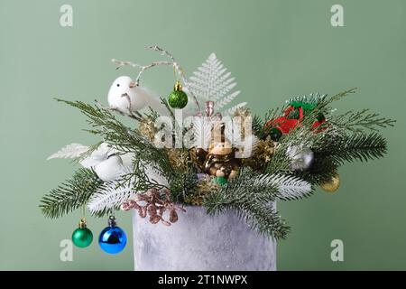 Weihnachtskomposition in samtgrauer Box mit Fichte, Farn zur Tischdekoration. Verschneite Strähnen mit Wackeln, Vogel in wunderschöner Verpackung, zusammengebaut von Stockfoto