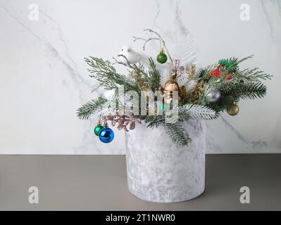 Weihnachtskomposition in samtgrauer Box mit Fichte, Farn zur Tischdekoration. Verschneite Strähnen mit Wackeln, Vogel in wunderschöner Verpackung, zusammengebaut von Stockfoto