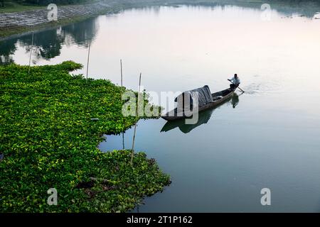 Ein einheimischer Fischer auf dem Rücken eines Kanus mit Fischern, rudert auf dem Brahmaputra River bei Sonnenuntergang auf Majuli Island, Assam, Indien Stockfoto