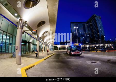 Ein öffentlicher TTC-Bus fährt an einem Bahnsteig in der neu renovierten Victoria Park Station vorbei. Ein Appartementgebäude in der Ferne. Stockfoto