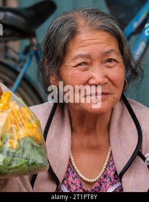 Long Khe, Provinz Bac Ninh, Vietnam. Eine Frau mittleren Alters mit ihren Marktkäufen. Stockfoto