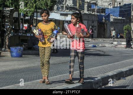 Rafah, Palästinensische Gebiete. Oktober 2023. Palästinensische Mädchen tragen Wasserflaschen in Rafah, südlich des Gazastreifens, während die Kämpfe zwischen israelischen Truppen und islamistischen Hamas-Kämpfern fortgesetzt werden. Abed Rahim Khatib/dpa/Alamy Live News Stockfoto