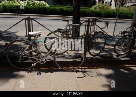 Drei Fahrräder, die an einem Geländer auf einer Straße im Zentrum von Lyon, Frankreich, befestigt sind. Ein Unisex-Rahmen, ein Rennrad für Herren und das Hinterrad eines MTN-Bikes. Stockfoto