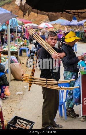 Cau Marktszene, Vietnam. Hmong man mit traditionellen Blasinstrumenten, dem Khen Mong oder Qeej. Provinz Lao Cai. Stockfoto