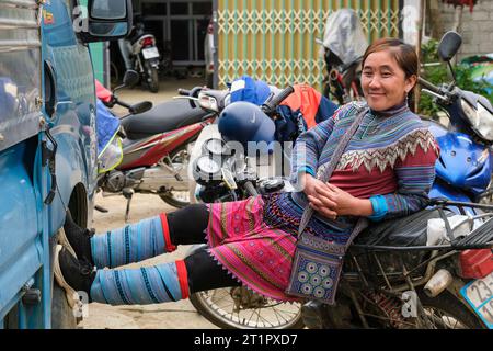 Bac Ha, Vietnam. Junge Frau, die sich im traditionellen Hmong-Kleid entspannt. Provinz Lao Cai. Stockfoto