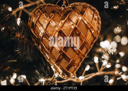 Weihnachtsbaum mit goldenem Herzspielzeug. Feendetails, Bokeh Lichter, festliche Winterferien im Hintergrund Stockfoto