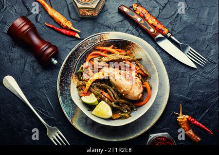 Gebratenes Hähnchen mit Gemüsegarnierung und Gewürzen. Geschmorte Hähnchenschenkel. Stockfoto