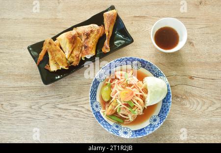 Som tum thailändischer würziger grüner Papaya-Salat mit gebratenem Hähnchenfleisch auf Teller, Dippen mit scharfer Sauce Stockfoto