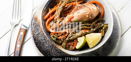 Gebratenes Hähnchen mit Gemüsegarnierung und Gewürzen. Geschmorte, würzige Hähnchenschenkel. Stockfoto