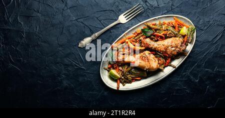 Gebratenes Hähnchen mit Gemüsegarnierung und Gewürzen. Geschmorte Hähnchenschenkel. Stockfoto