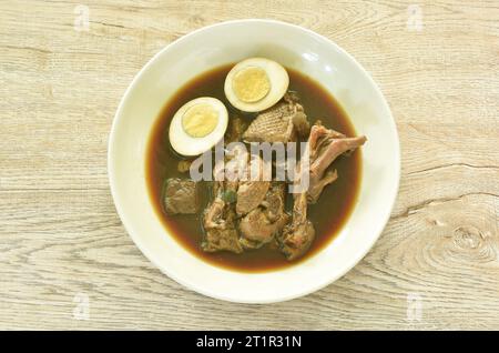 Gekochtes, halbgeschnittenes Ei mit geschmortem Entenfleisch und Fuß in brauner chinesischer Kräutersuppe auf Teller Stockfoto