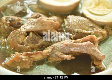 Gekochtes, halbgeschnittenes Ei mit geschmortem Entenfleisch und Fuß in brauner chinesischer Kräutersuppe auf Teller Stockfoto
