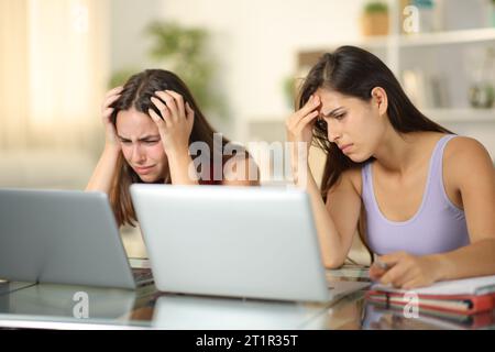 Traurige Schüler, die schlechte Noten auf Laptops zu Hause überprüfen Stockfoto