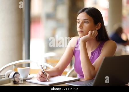 Demotivierter Student, der auf einer Restaurantterrasse sitzt Stockfoto