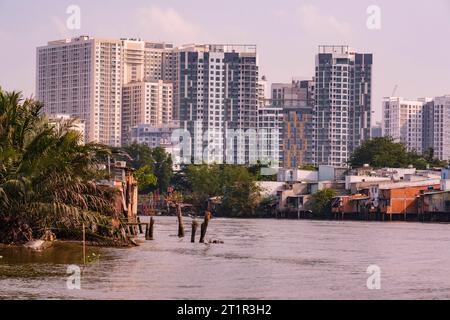 Saigon Riverside View in der Nähe von Ho Chi Minh, Vietnam. Gegenüberstellung von modernen Hochhauswohnungen mit bescheidenen Wohnhäusern der unteren Klasse. Stockfoto