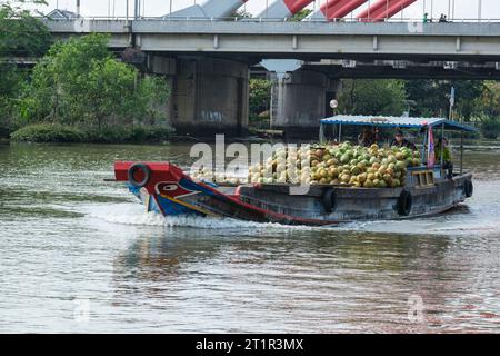 Flussverkehr auf dem Saigon River, der Kokosnüsse zum Markt bringt, in der Nähe von Ho Chi Minh, Vietnam. Schwarze Augen im White Circle am Prow of Boat sind traditionelle Prot Stockfoto