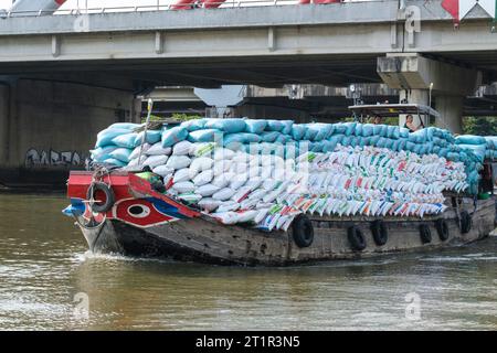 Flussverkehr auf dem Saigon River, in der Nähe von Ho Chi Minh, Vietnam. Black Eyes im White Circle am Prow of Boat sind der traditionelle Schutz gegen Evil River SPI Stockfoto