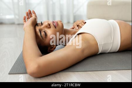 Unglückliche müde, schlanke junge lateinfrau in Sportbekleidung ruht vom Training im Wohnzimmer Stockfoto