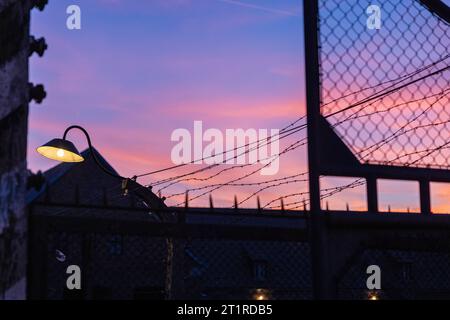 Denkmal Konzentrationslager Auschwitz I Polen, Auschwitz am 11.10.2023: Stacheldraht und Strassenlampe/Laterne am Zaun vorm Lila blauer Himmel am Eingang vom Denkmal Auschwitz I.. *** Denkmal Konzentrationslager Auschwitz I Polen, Auschwitz am 11 10 2023 Stacheldraht und Straßenlaterne auf dem Zaun vor dem violetten blauen Himmel am Eingang des Denkmals Auschwitz I Credit: Imago/Alamy Live News Stockfoto