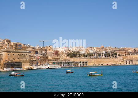 Valletta, Malta - 17. Juni 2023: Golf zwischen Valletta und Vittoriosa mit vorbeifahrenden Booten und typischen Luzzu und Valletta im Hintergrund Stockfoto