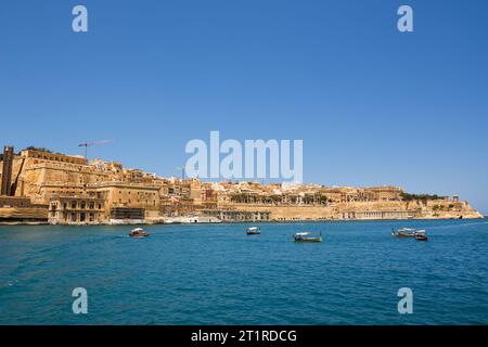 Valletta, Malta - 17. Juni 2023: Golf zwischen Valletta und Vittoriosa mit vorbeifahrenden Booten und typischen Luzzu und Valletta im Hintergrund Stockfoto